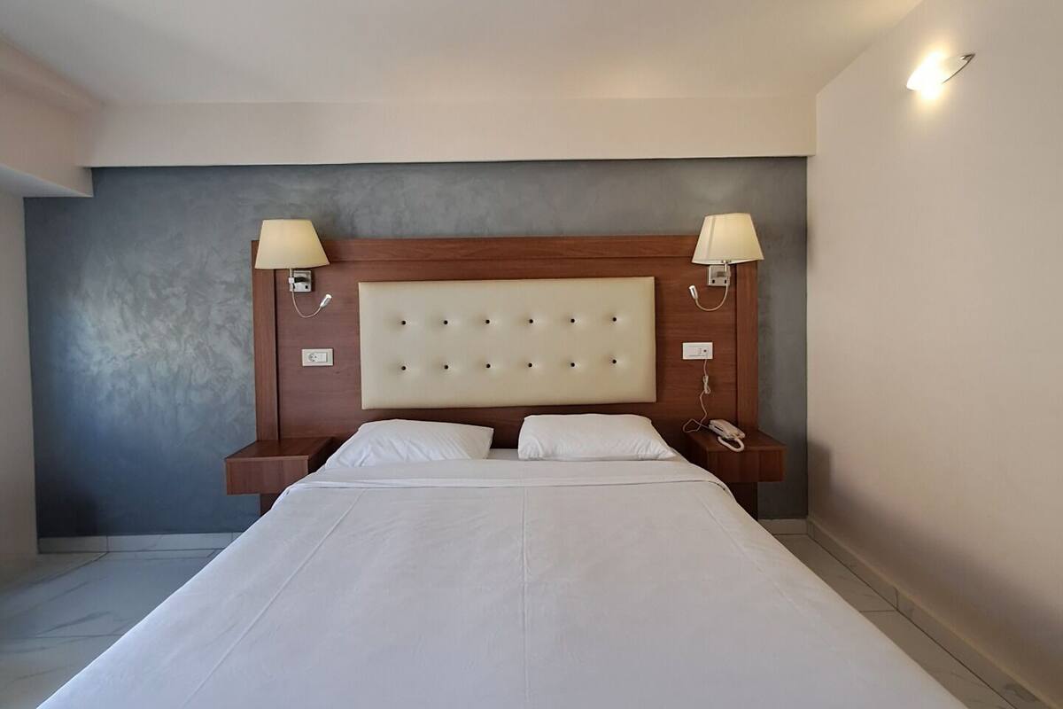 A hotel room with a large bed, a wooden headboard, bedside lamps, and a telephone.