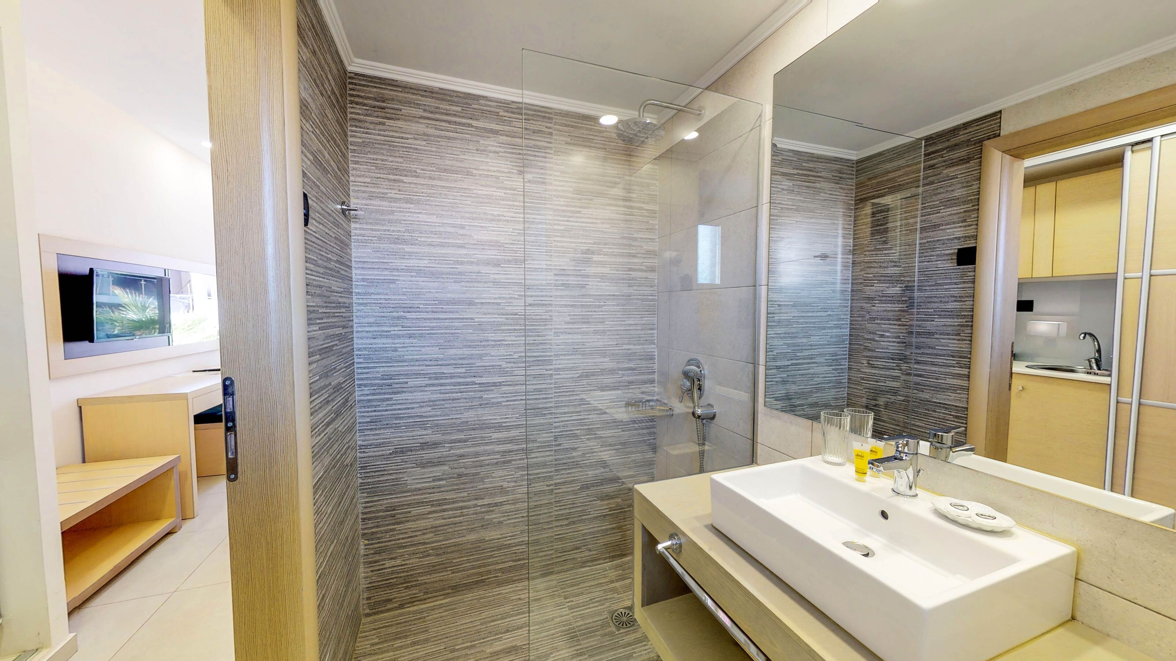 Een moderne badkamer met een glazen douchecabine, een grote spiegel en een wit wastafelmeubel.