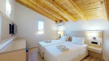 A hotel room with a wooden ceiling, two beds, a TV, a window, and a bedside lamp.