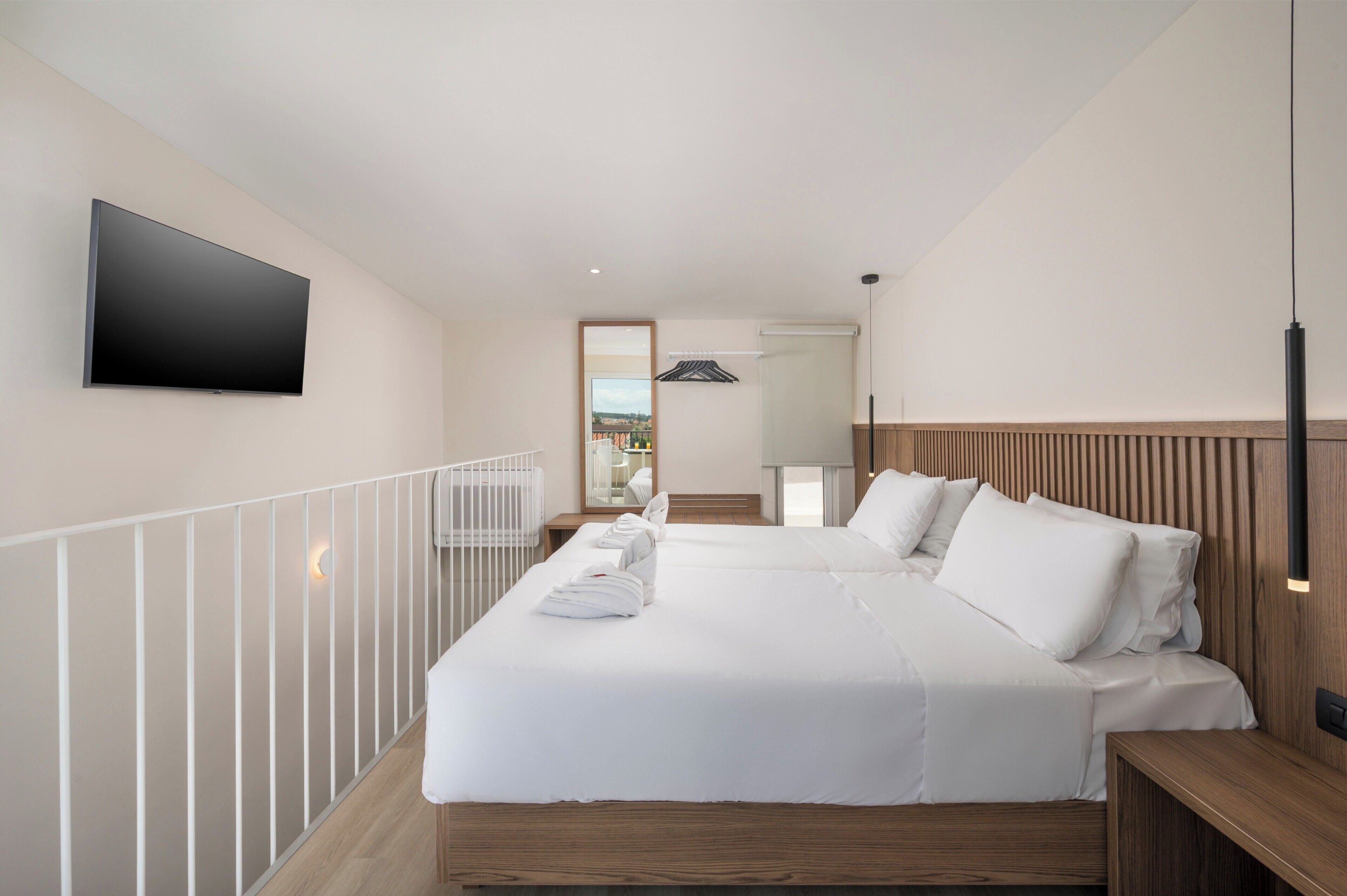 Habitación de hotel con una cama grande, televisión de pantalla plana, cabecero de madera y vistas a la ciudad.