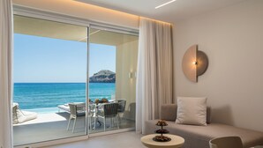 Habitación de hotel moderna con puerta de cristal que da a un balcón con vistas al mar y a la montaña.