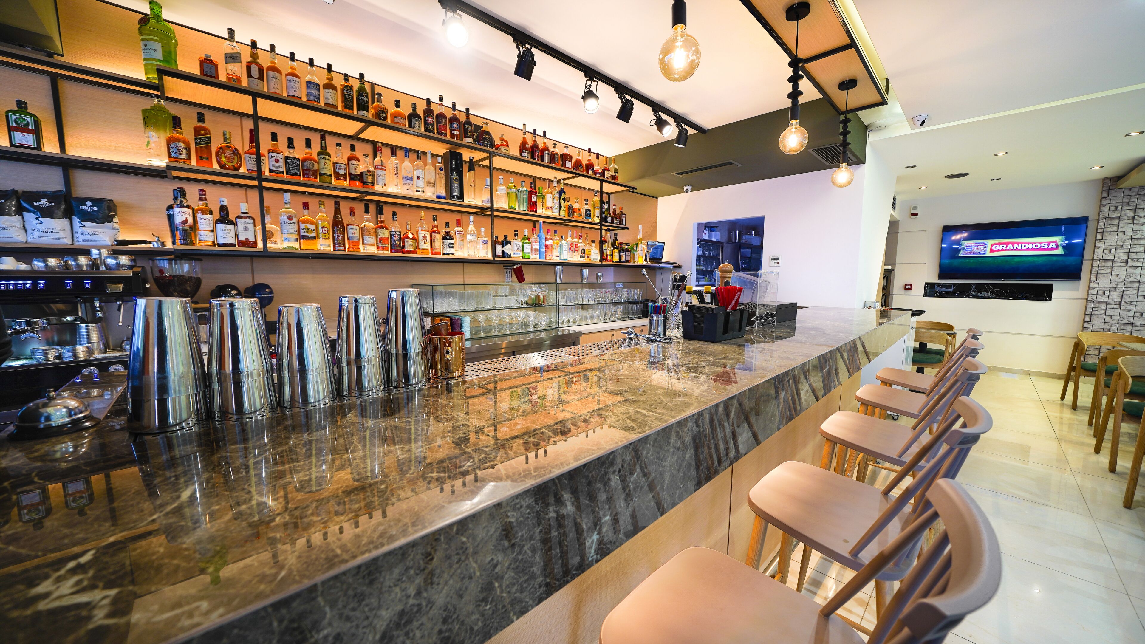 A bar area with a marble countertop, multiple bar stools, and a variety of liquor bottles on shelves.