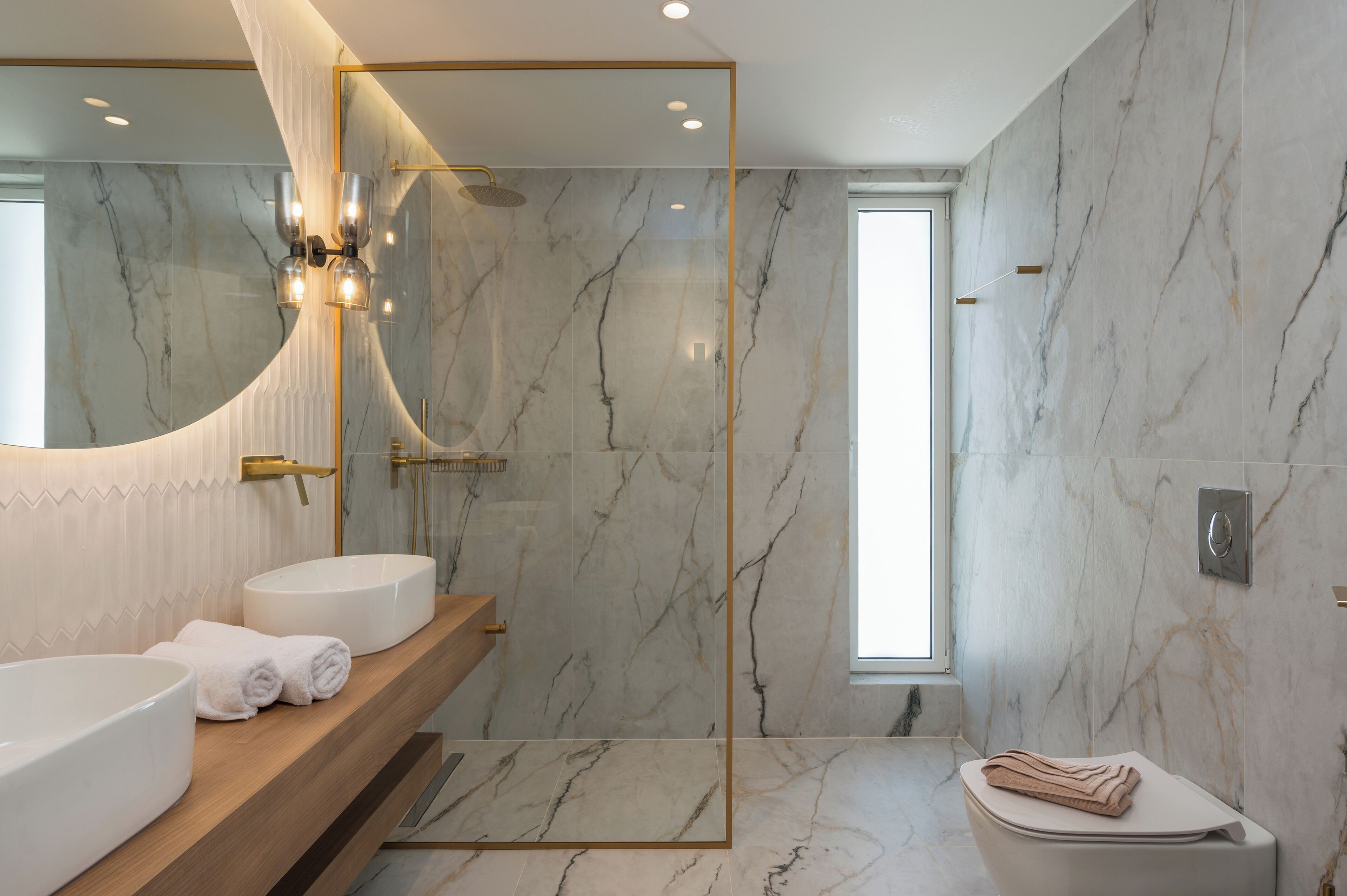 Un baño moderno con un espejo grande, dos lavamanos, una ducha y un inodoro.