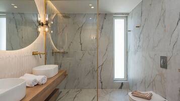 Un baño moderno con un espejo grande, dos lavamanos, una ducha y un inodoro.