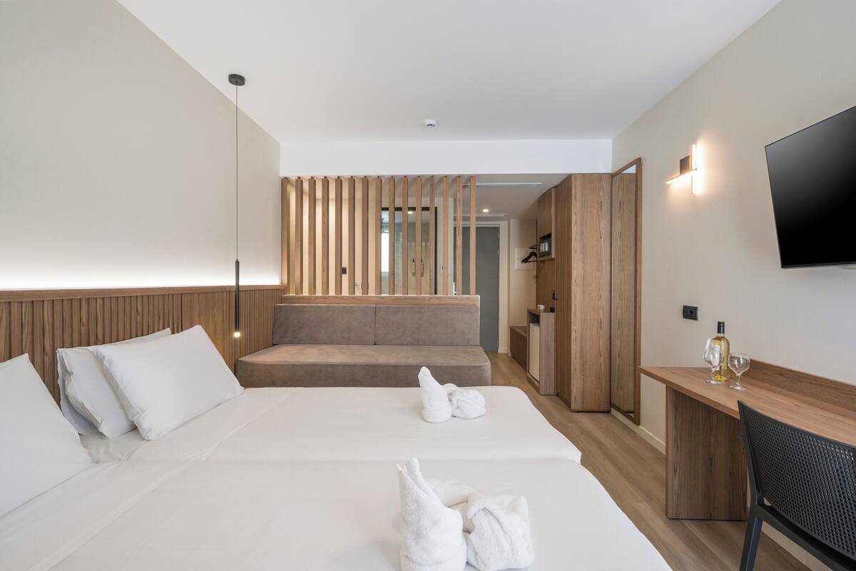 A hotel room with a bed, a desk, a TV, and a staircase leading to another room.