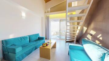 A modern living room with a teal sofa, a wooden coffee table with fruit, and a staircase leading to a balcony.