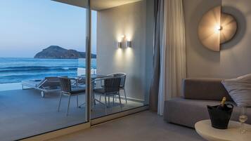 A balcony with a glass door, a table with chairs, a sofa, a wall-mounted light fixture, and a bottle of champagne.