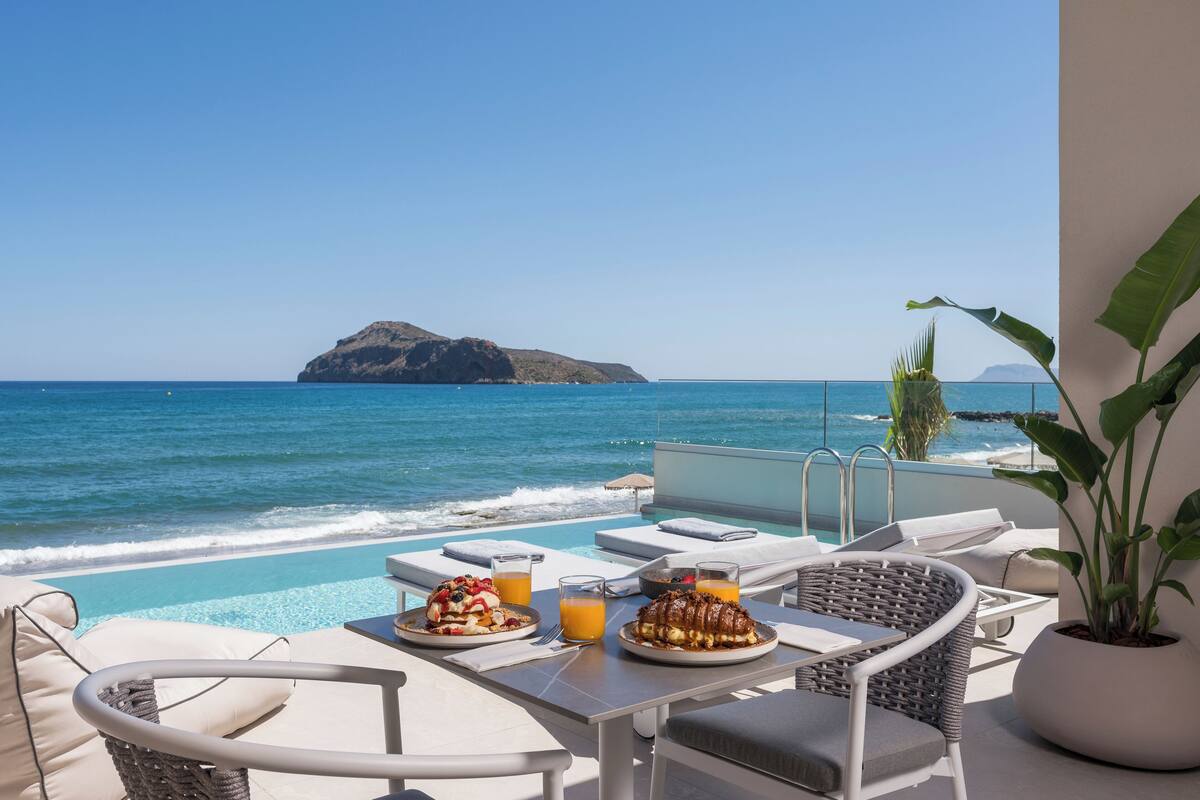 A poolside dining area with a view of the ocean and a distant island.