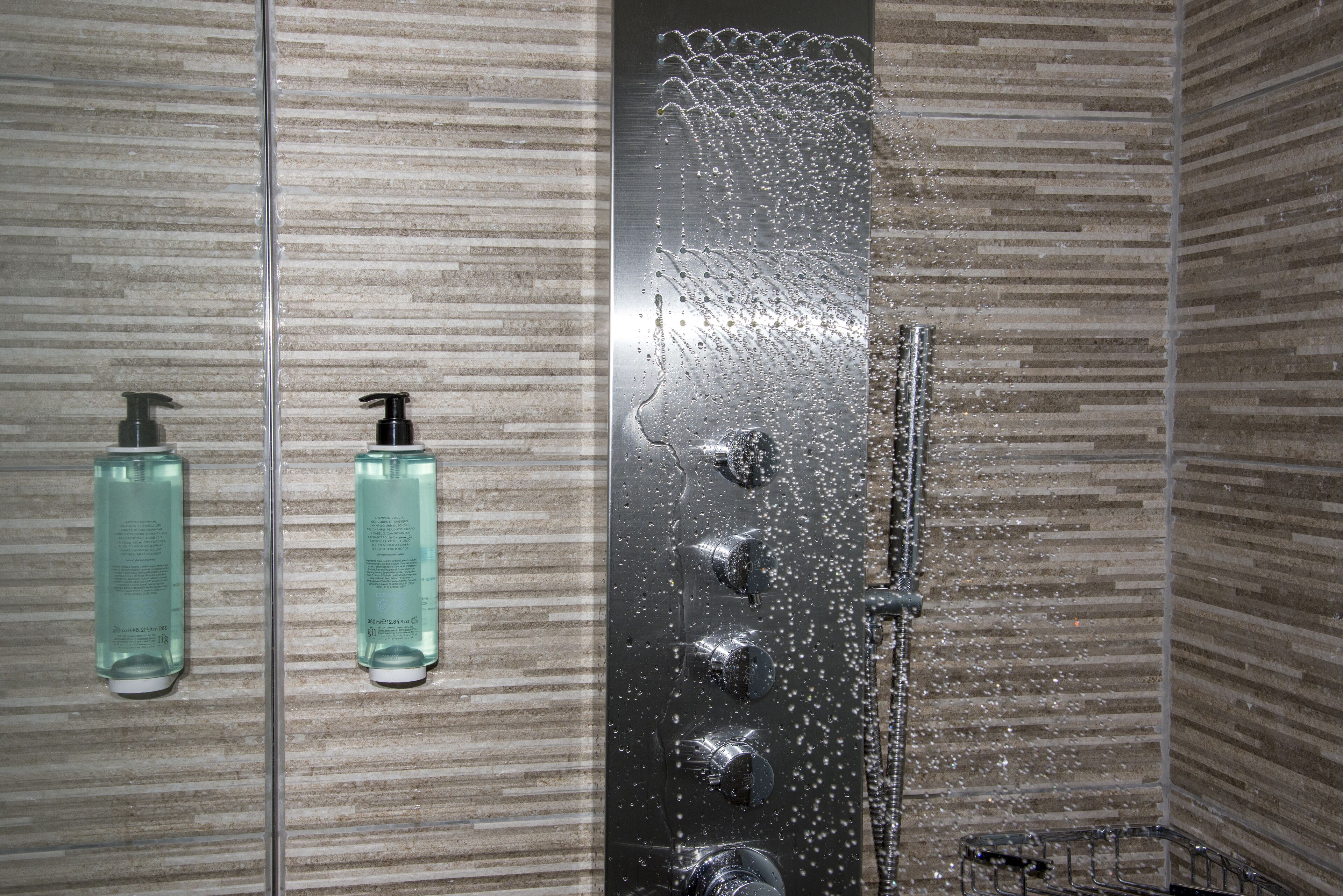 Eine Dusche mit Regendusche und zwei Shampoo-Flaschen an der Wand.