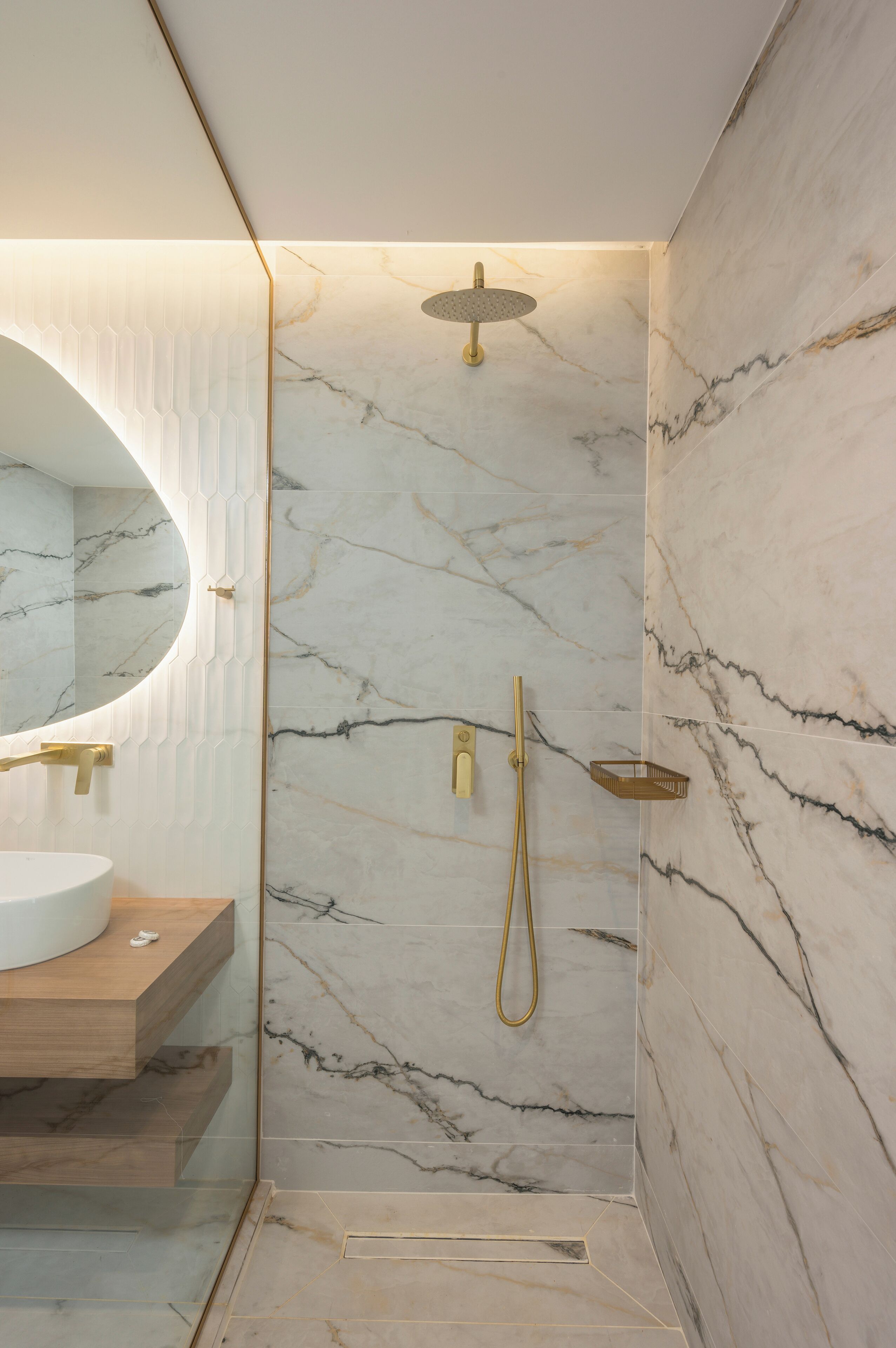 Une salle de bain moderne avec une douche en marbre, un meuble-lavabo en bois et un grand miroir.
