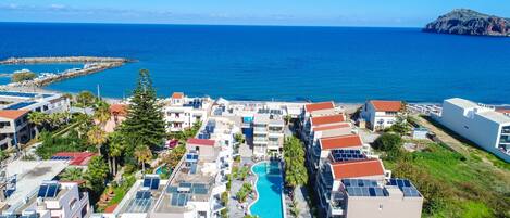 A coastal resort with a swimming pool, solar panels, and a view of the sea.
