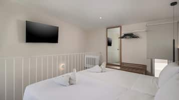 A hotel room with a large bed, a flat-screen TV mounted on the wall, a radiator, and a mirror.