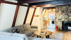 Ein gemütliches Wohnzimmer mit einer Eckcouch, einem Holztisch und einem Kamin aus Stein.