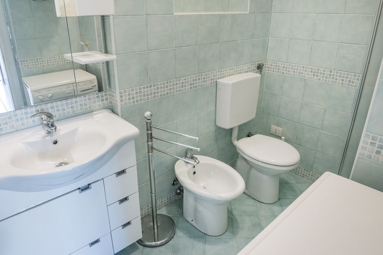 Et badeværelse med vask, toilet og spejl.