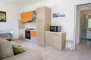 A compact kitchen with a microwave, oven, and orange cabinets.