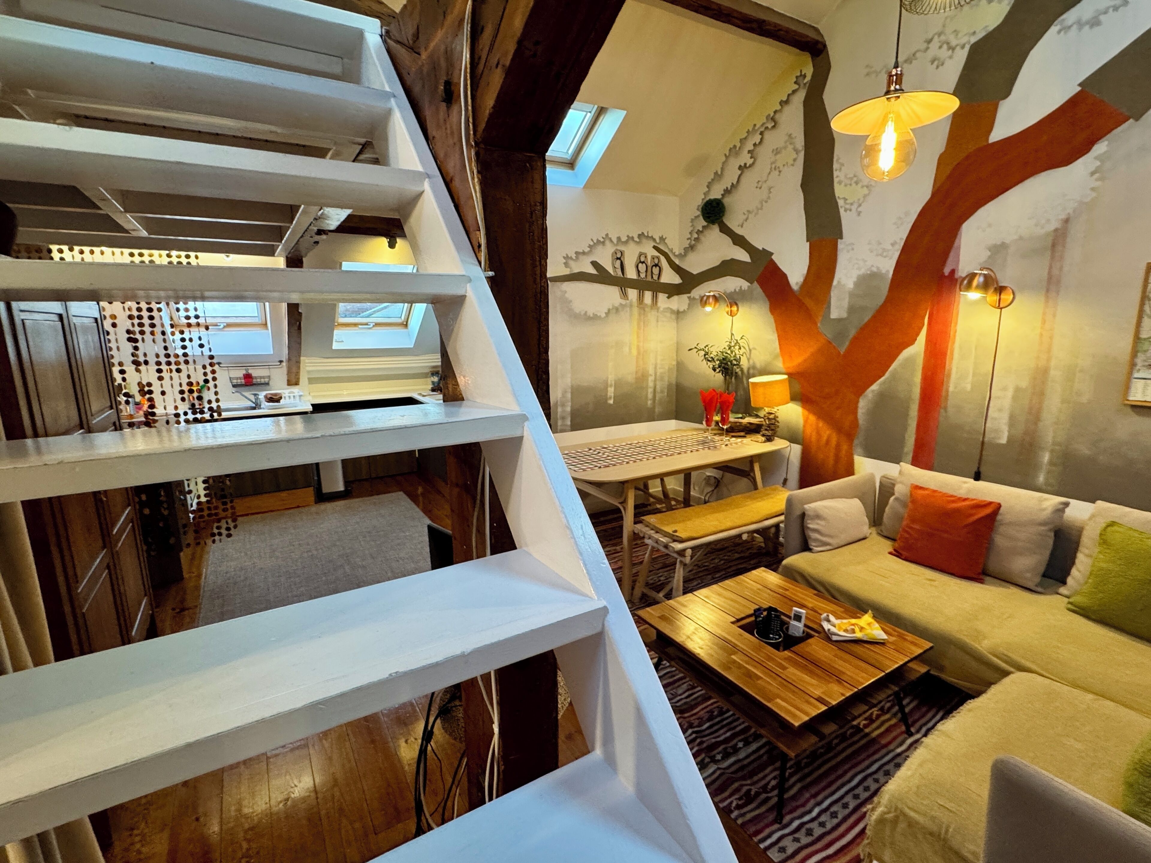 A multi-level living space with a staircase, a dining area, and a sofa.