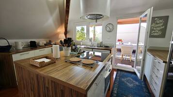 Una cocina moderna con isla de madera, estufa integrada y comedor con vistas.
