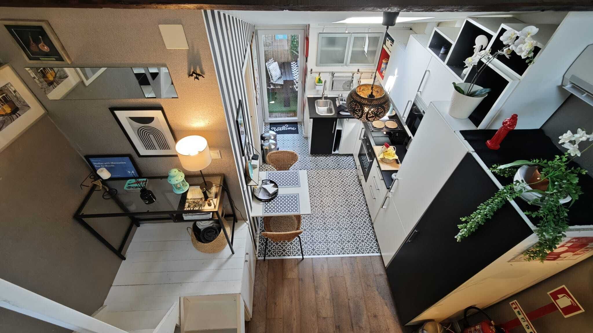 Cocina compacta con comedor, un pequeño rincón de descanso y un espacio exterior visible a través de una puerta corrediza.