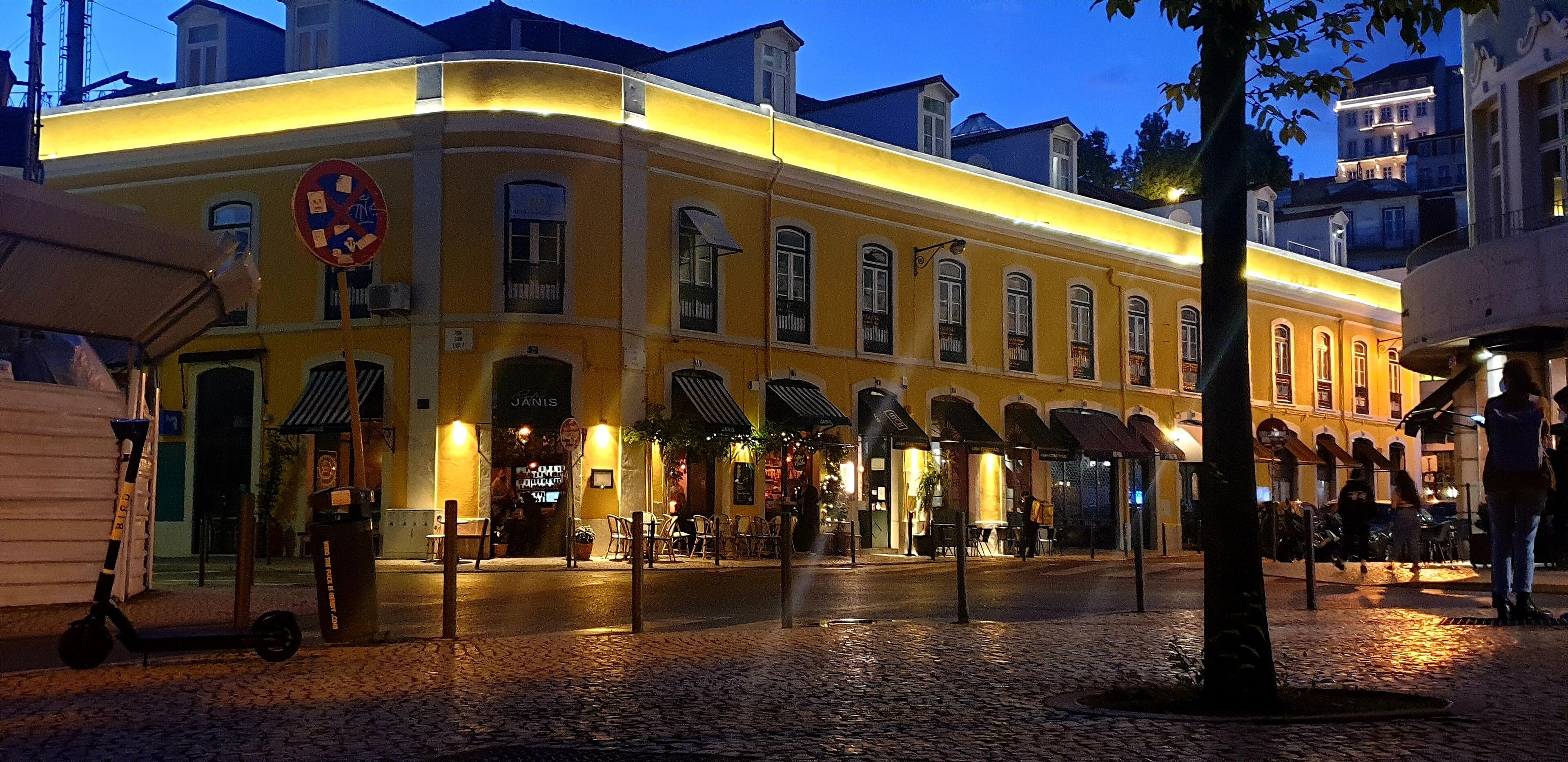 A historic building with a yellow facade, multiple windows, and outdoor seating areas.