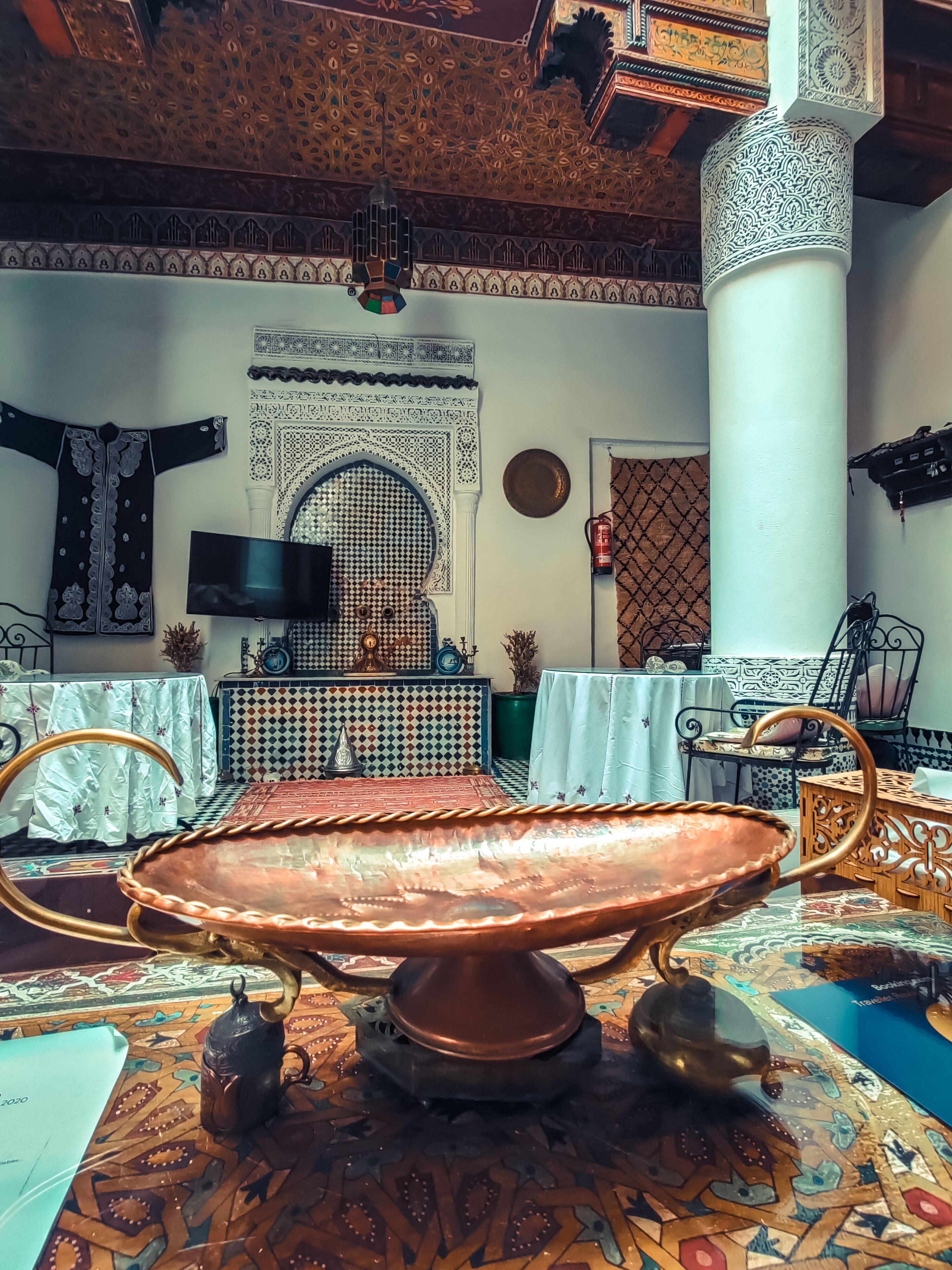 A traditional room with a large, ornate coffee table, a flat-screen TV, and a patterned carpet.