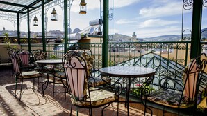 A covered outdoor seating area with metal chairs and tables, overlooking a cityscape. - Ryad Zahrat Fes (Fes)