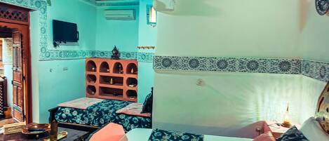 A room with two beds, a wooden ceiling, and patterned walls.