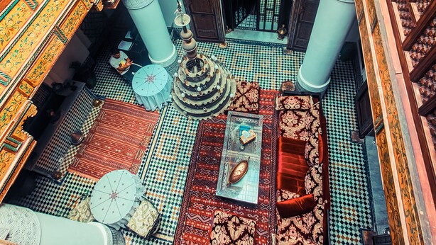 A traditional interior with ornate wooden railings, a patterned floor, and a central decorative piece. - Ryad Zahrat Fes (Fes)