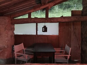 A rustic wooden room with a table and two chairs, a hanging lantern, and a window with a view of greenery outside. - Mansion - Caravate (Caravate)