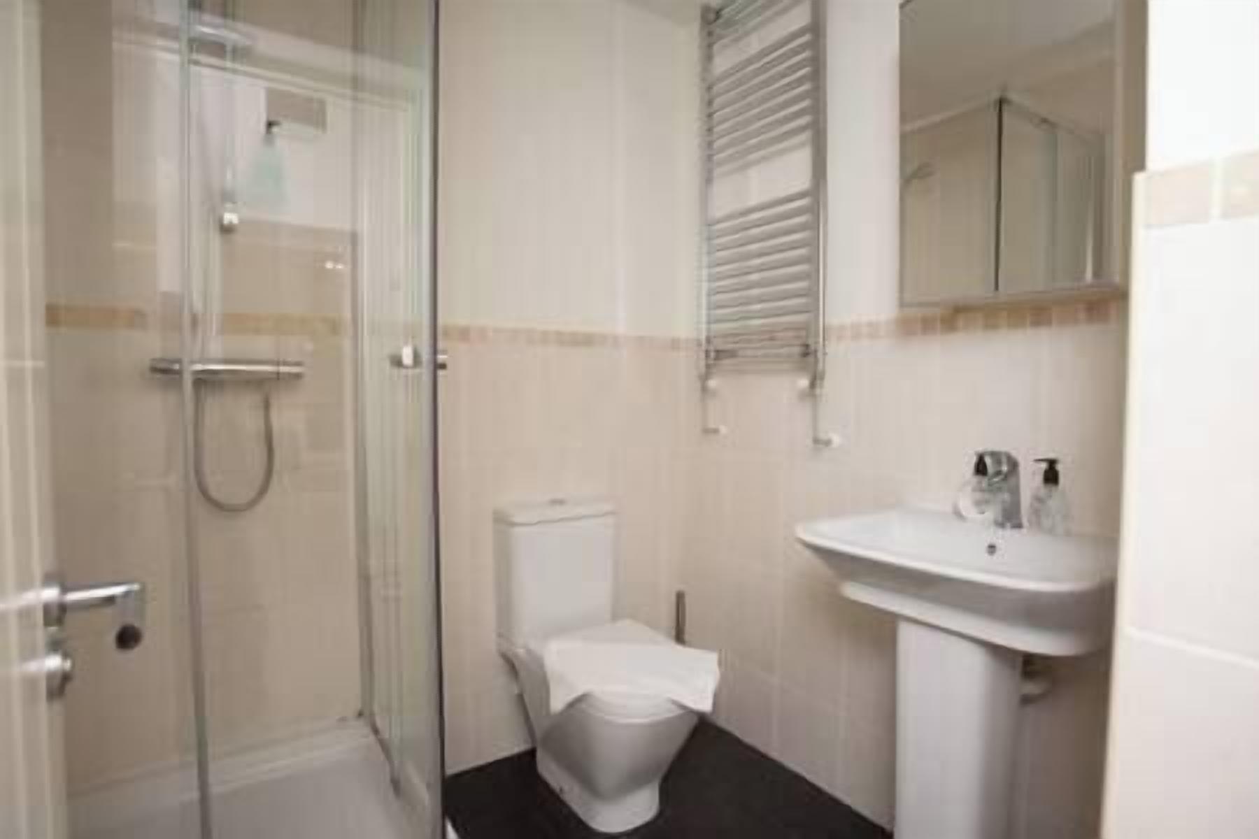 A bathroom with a glass shower enclosure, a toilet, and a pedestal sink.