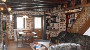A rustic interior with a stone wall, wooden furniture, and a staircase. - Charming independent cottage with enclosed garden, pets allowed (La Petite-Marche)