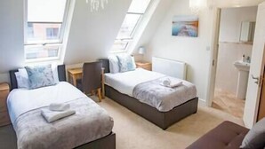 Ein modernes Schlafzimmer mit zwei Betten, einem Schreibtisch und einer Kristallleuchtre.