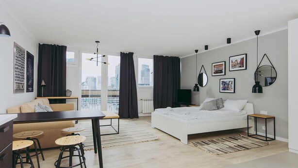 En modern lägenhet med en säng, en soffa, ett matbord och ett köksutrymme.