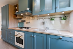 A kitchen with teal cabinetry, a stove, oven, and a sink.