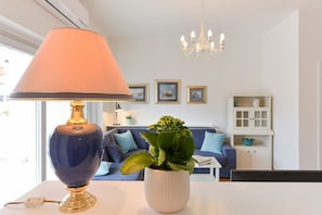 A modern living room with a blue lamp, a white vase with green plants, a blue sofa, and a white cabinet.
