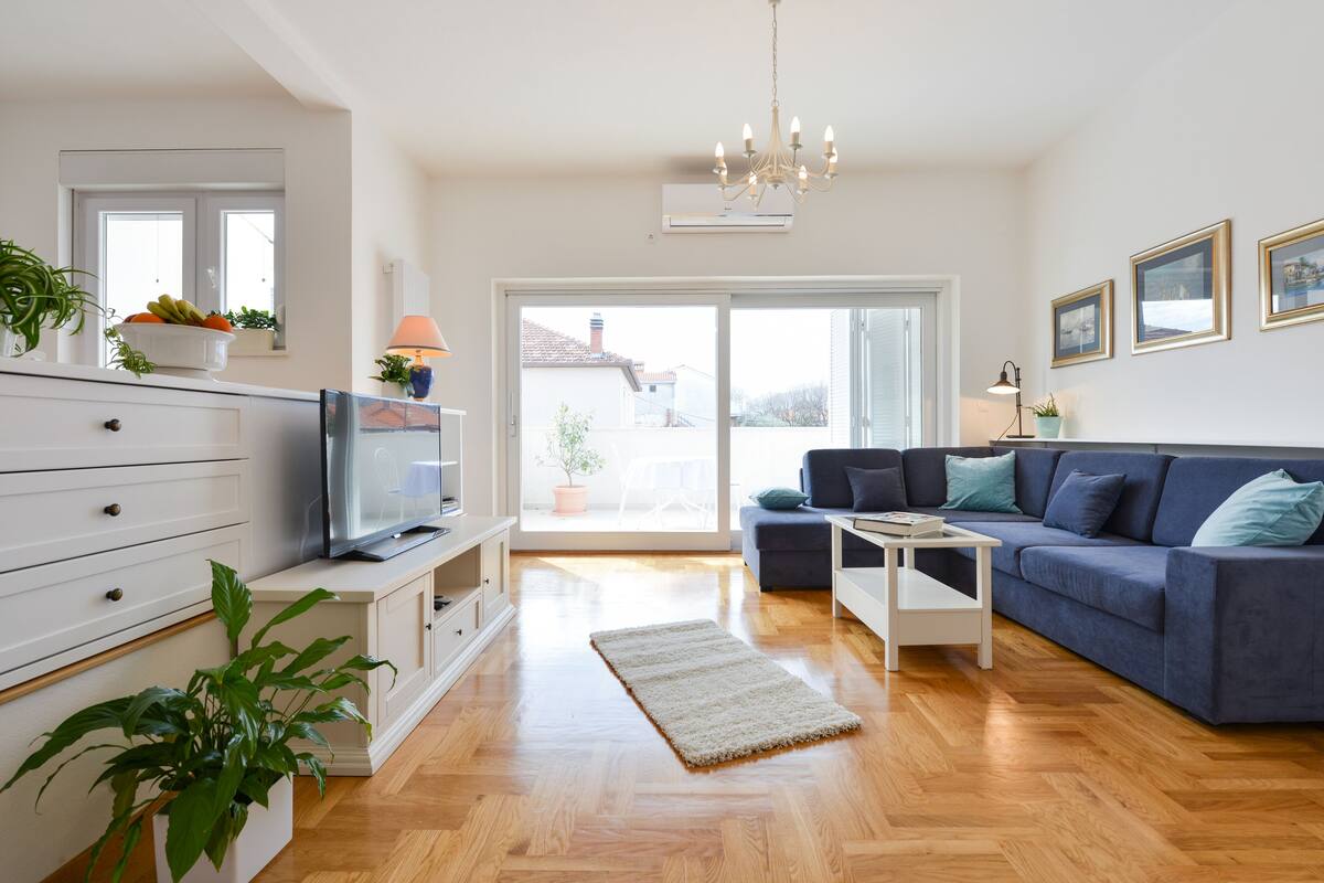 A modern living room with a sofa, TV, and plants.