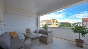 A balcony with a wicker sofa, a table, and a potted plant. - Spacious Chic Residence (Zadar)