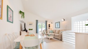 A modern, well-lit living area with a dining table, chairs, a sofa, and a kitchen area. - Spacious Chic Residence (Zadar)