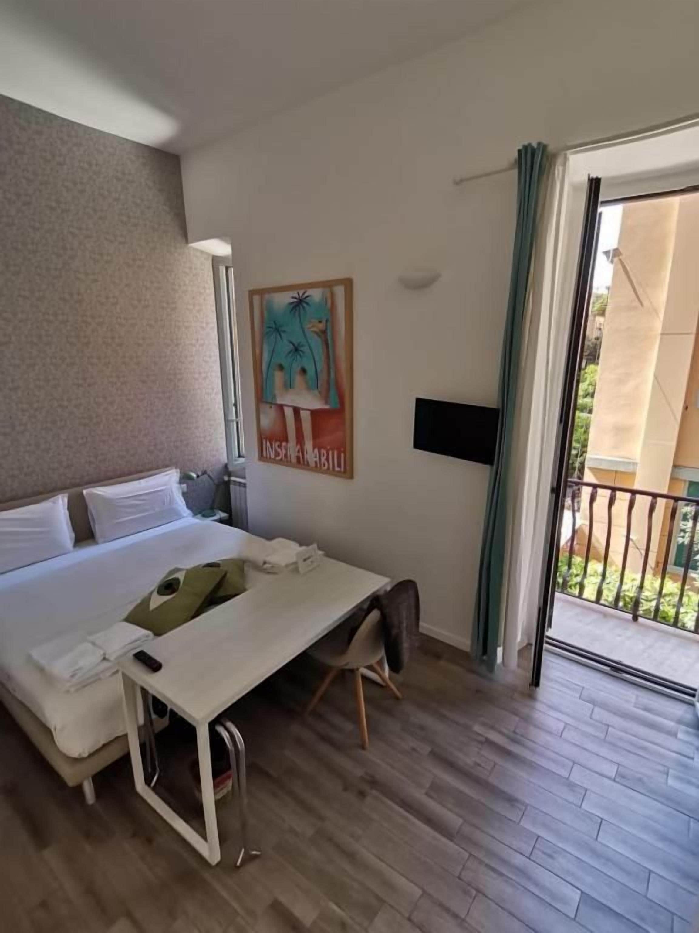 A hotel room with a bed, a desk, a chair, a TV, and a balcony.