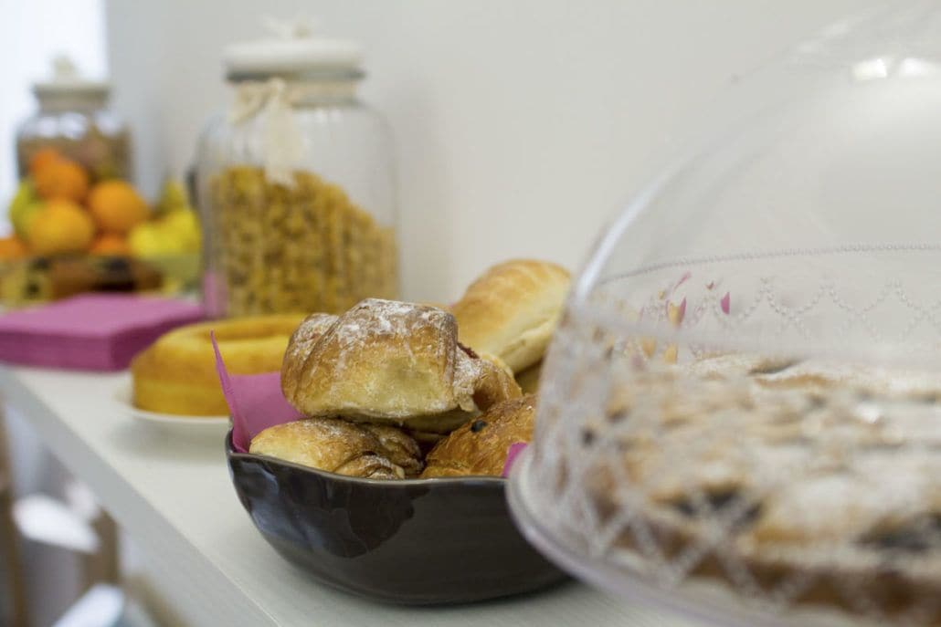 Une table avec un saladier rempli de viennoiseries et un bocal de granola.