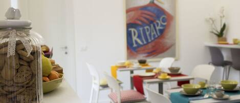 Un comedor con una mesa dispuesta para cuatro, un tarro de galletas y un cuadro en la pared.