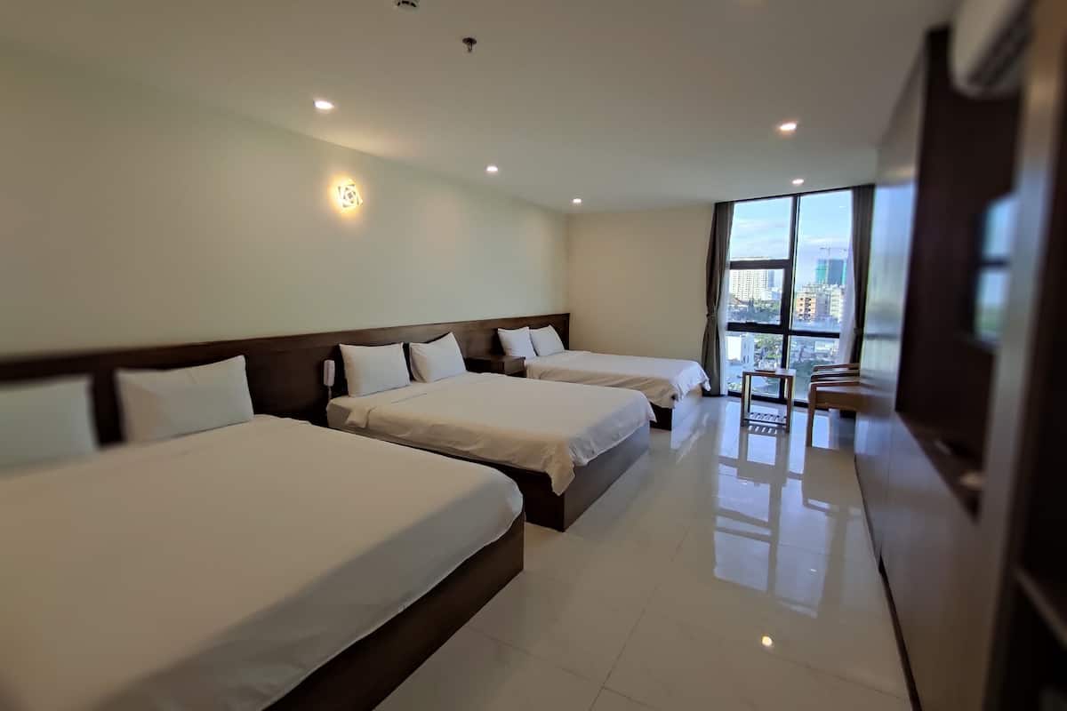A hotel room with three beds, a large window with a city view, and a modern design.