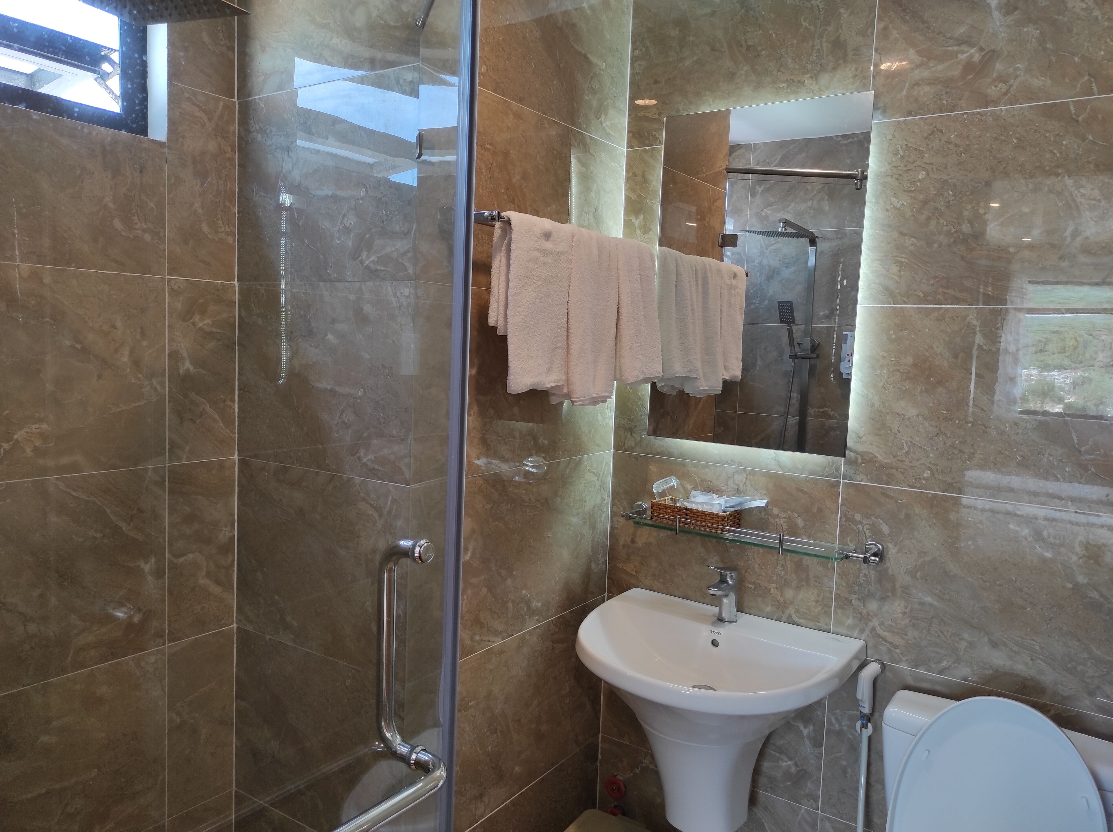 A modern bathroom with a glass shower enclosure, a white sink, and a toilet.
