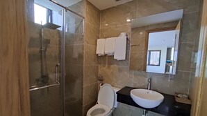 A modern bathroom with a glass-enclosed shower, a white toilet, a black countertop with a white sink, and a mirror above the sink. - Hong Hai 2 Hotel (Ho Chi Minh City)