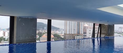 Una amplia piscina interior con vistas claras a edificios circundantes y una montaña distante.