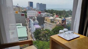 A view from a window overlooking a cityscape with buildings and a distant body of water. - Hong Hai 2 Hotel (Ho Chi Minh City)