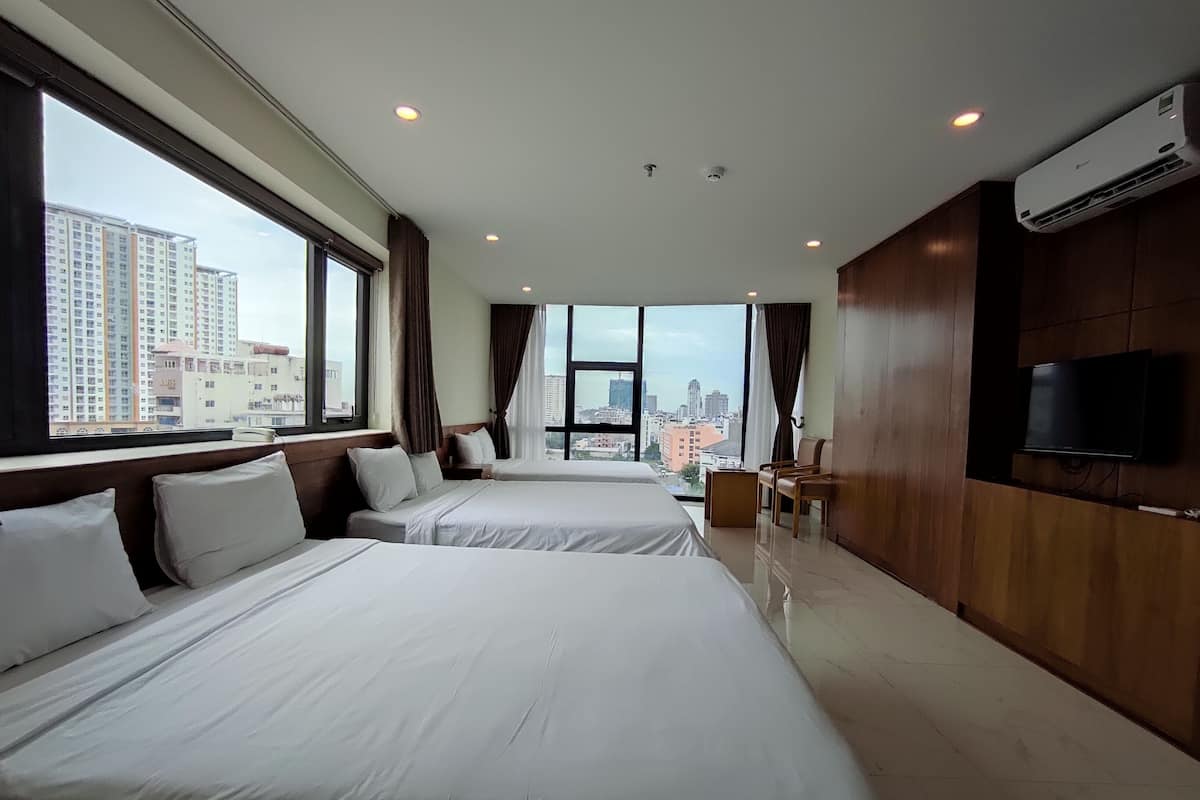 A hotel room with two beds, a TV, and a city view.