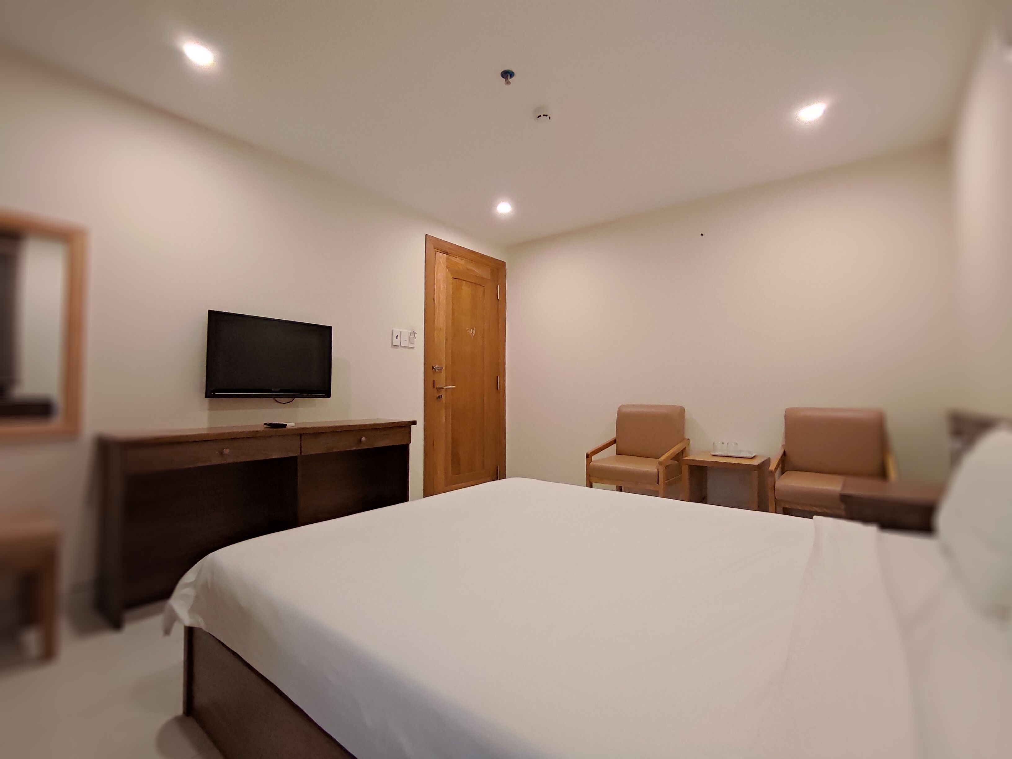 Una habitación de hotel con una cama, un escritorio, un televisor y dos sillas.