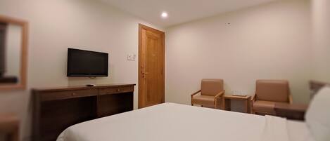 Una habitación de hotel con una cama, un escritorio, un televisor y dos sillas.