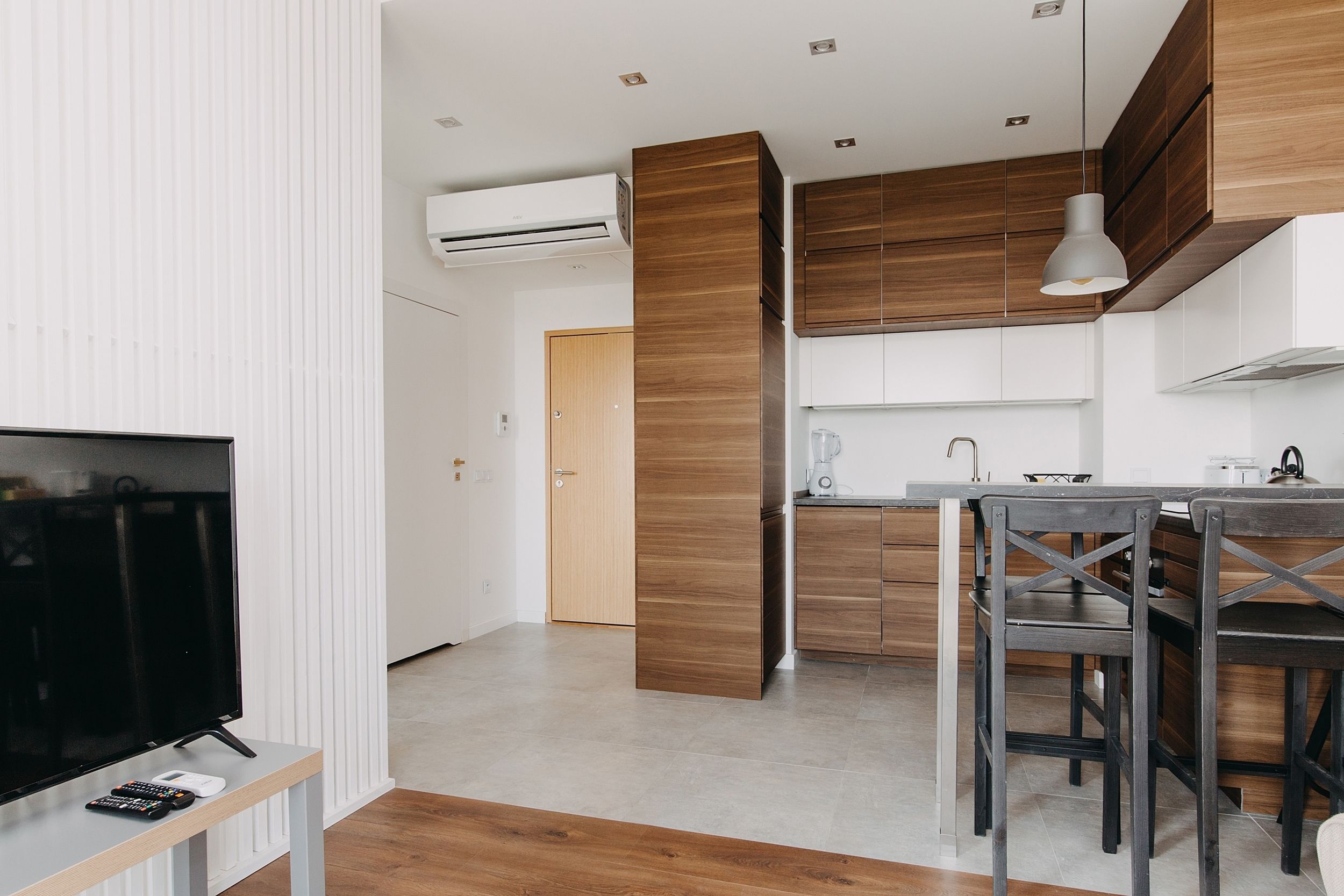 Una cocina moderna con armarios de madera, un comedor con mesa y sillas, y un televisor sobre un mueble bajo.