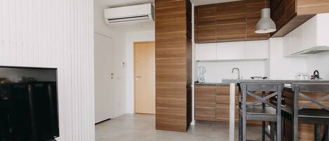 Una cocina moderna con armarios de madera, un comedor con mesa y sillas, y un televisor sobre un mueble bajo.